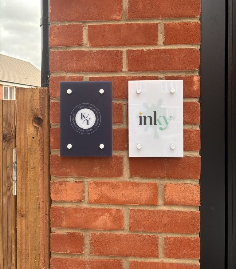 Inky and K/Y signage mounted side by side on the brick wall by the studio door