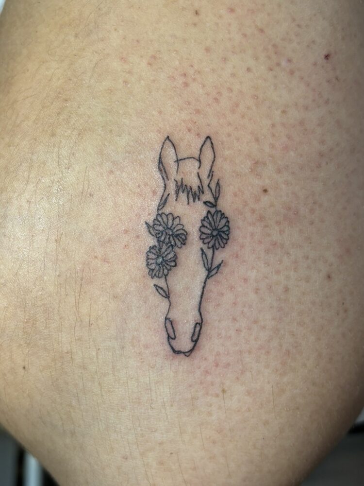Fine line horse and daisy tattoo