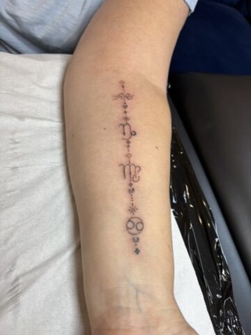 Fine line zodiac symbol chain tattoo on the forearm